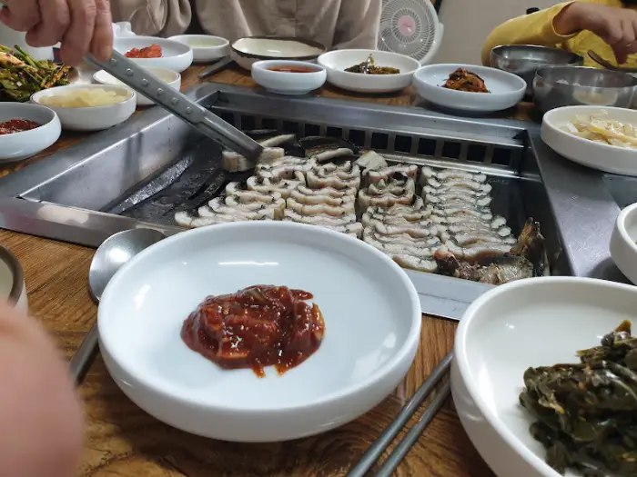 장어를 굽고 있는 모습과 함께 다양한 반찬이 준비된 테이블