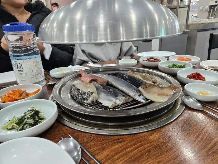 숯불 위에서 구워지고 있는 생선들을 보여주는 클로즈업 샷