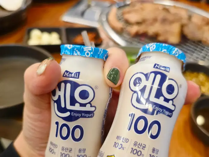 두 개의 요거트 병을 들고 있는 손