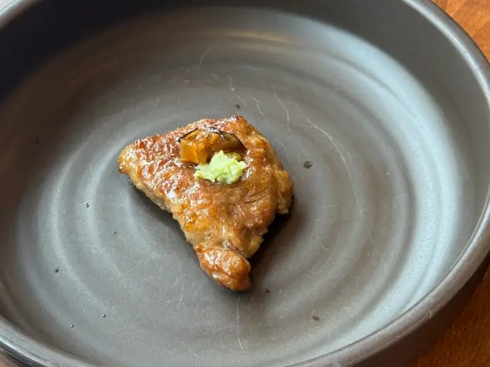 작은 접시에 담긴 맛있게 구워진 고기 한 점과 와사비