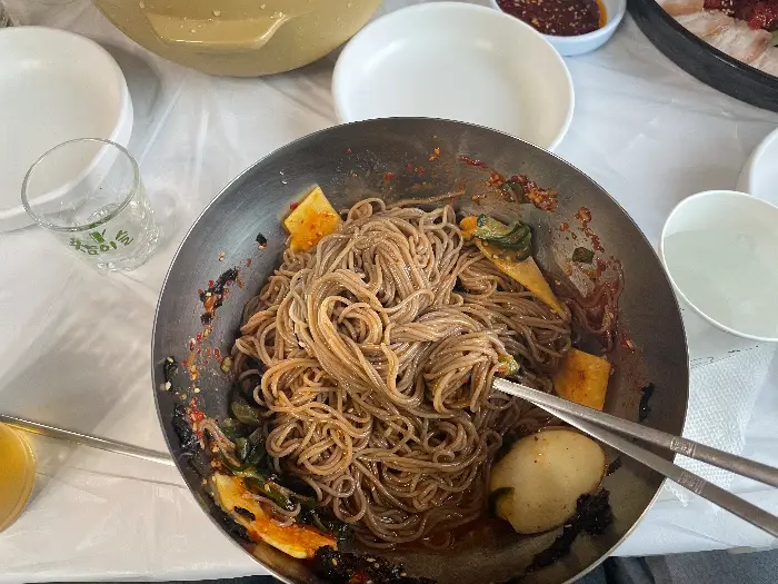 막국수 그릇에 담긴 면과 양념, 그리고 곁들임 찬