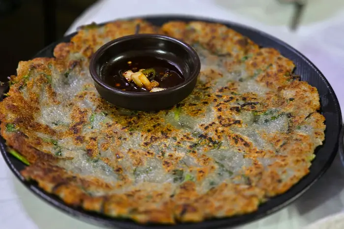 동그랗게 부쳐진 감자전 위에 작은 종지에 담긴 양념장이 올려져 있다.