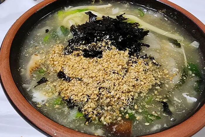 옹심이 뚝배기 위에 김가루와 깨, 파가 넉넉하게 올라가 있다.