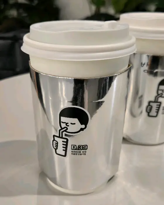은색 홀더가 씌워진 테이크아웃 커피잔