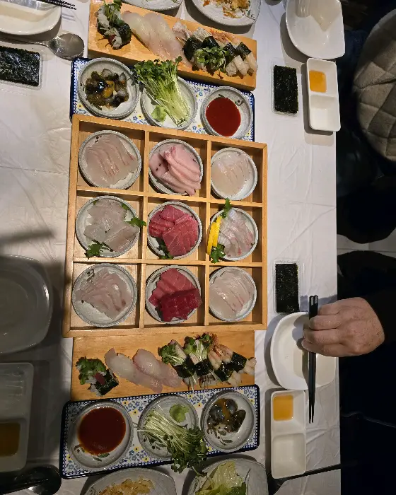 테이블에 여러 가지 종류의 회와 초밥, 곁들임 메뉴들이 푸짐하게 차려져 있는 모습