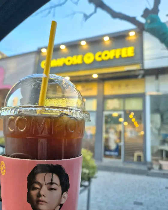 컴포즈커피 매장 외관 사진, 저녁 시간에 조명이 켜져 있음