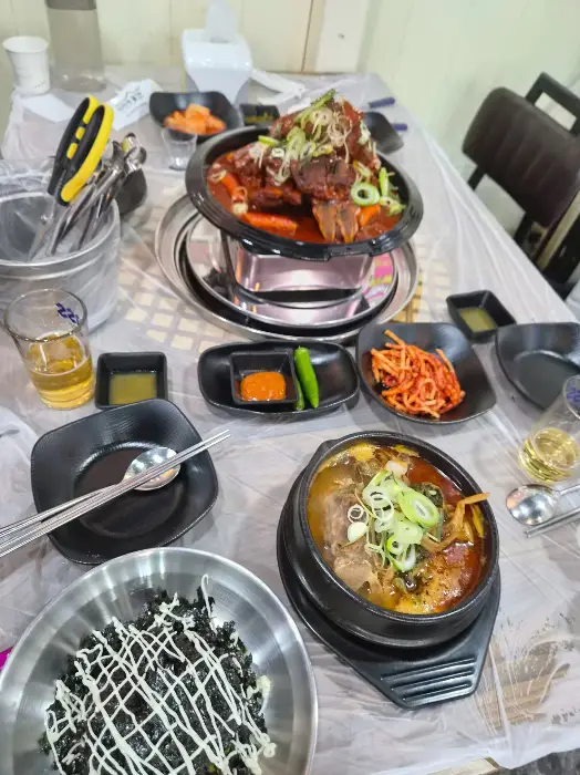 테이블 위에 차려진 푸짐한 한상차림, 뼈구이와 감자탕, 그리고 밑반찬들