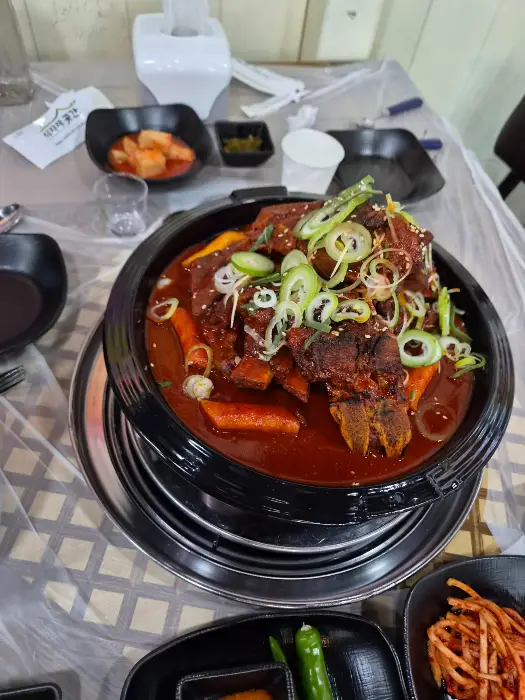 김이 모락모락 나는 뼈구이에 파채와 떡사리가 올려져 있는 모습