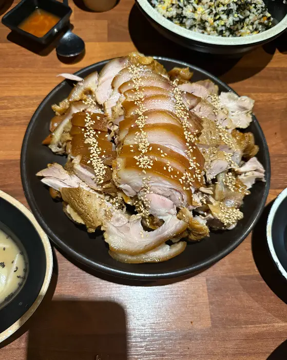 먹음직스럽게 썰어진 족발이 검은색 접시에 담겨 있다. 족발 위에는 참깨가 뿌려져 있다.