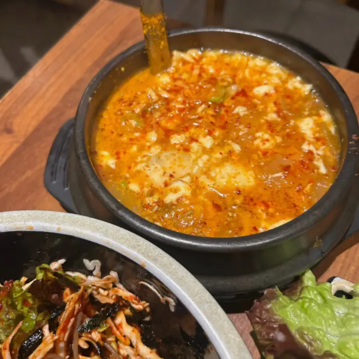 순두부찌개가 끓고 있는 모습. 붉은 국물에 순두부가 듬성듬성 보인다.