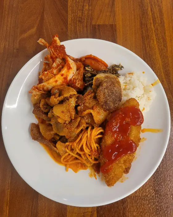 흰 쌀밥 위에 다양한 반찬과 생선까스가 올라간 모습