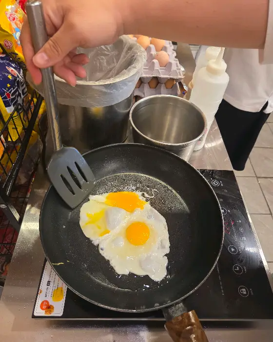 프라이팬에 계란후라이를 하고 있는 손의 모습