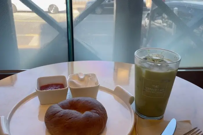 베이글과 함께 제공되는 크림치즈와 딸기잼, 그리고 녹색 음료