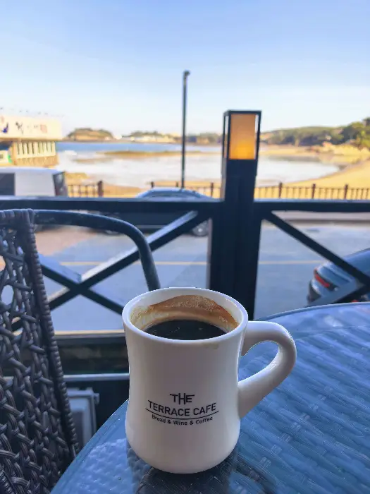 테이블 위에 놓인 머그잔에 담긴 커피와 창밖 바다 풍경