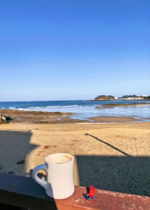 바다를 배경으로 놓인 흰색 머그잔과 작은 피규어