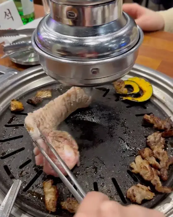 집게로 집어 올린 삼겹살 조각