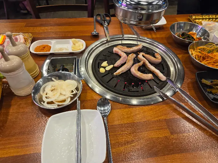 삼겹살이 구워지고 있는 불판과 곁들임 반찬