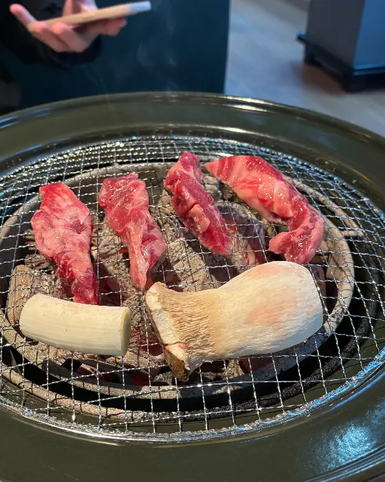 숯불 위에 놓인 고기 덩어리와 버섯, 파