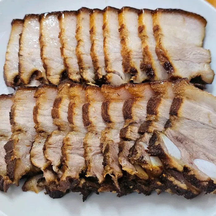 얇게 썰어 윤기가 흐르는 편육. 겹겹이 쌓인 살코기와 지방의 조화가 먹음직스럽습니다.