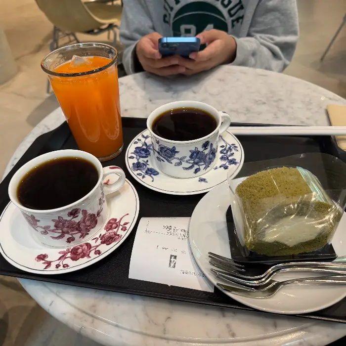 두 잔의 드립 커피와 녹차 케이크 한 조각이 놓인 테이블