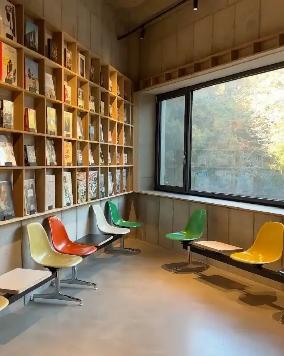 벽면 가득 책이 꽂힌 서점 공간과 형형색색의 의자들