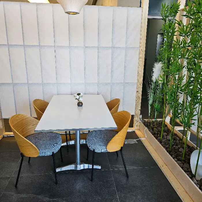 검은색 접시 위에 스테이크 한 조각이 놓여 있고, 그 주변으로 얇게 썬 채소와 소스가 곁들여져 있다.