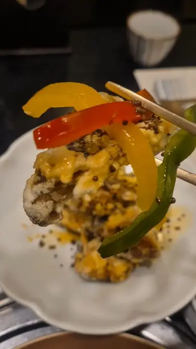 밝고 화사한 배경 앞에서 당당한 포즈를 취한 여성이 날개 달린 옷을 입고 있다.