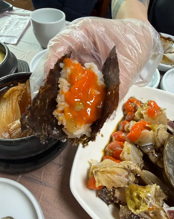 김 위에 밥과 간장게장을 얹어 먹는 모습