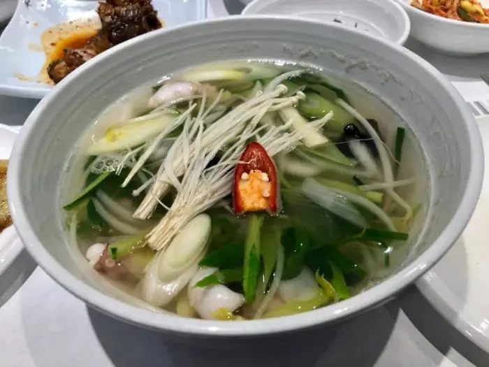 맑은 연포탕 안에 낙지, 채소, 버섯 등이 담겨 있는 모습