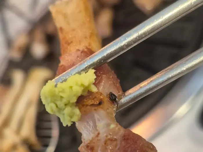 젓가락으로 집어 올린 불광옥 돼지갈비 조각과 쌈장