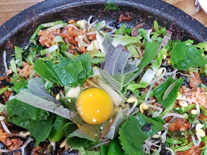 오리 양념 불고기 위에 신선한 채소와 계란이 올라간 모습