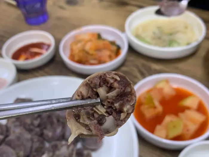 집게로 순대 한 조각을 집어 올린 모습, 속이 꽉 찬 것이 보인다.