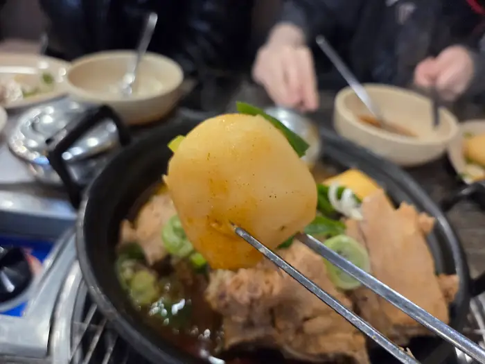 젓가락으로 감자탕 냄비 안의 통감자를 집어 올리는 모습