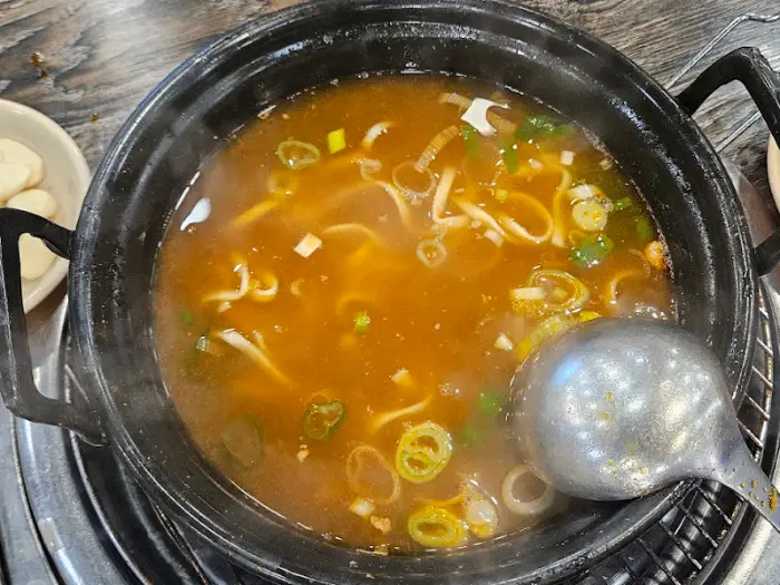 끓고 있는 감자탕 냄비에 국자로 떠낸 국물