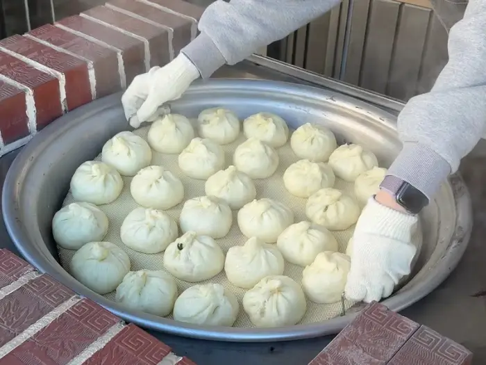 찜기 안의 찐빵들을 손으로 집는 모습
