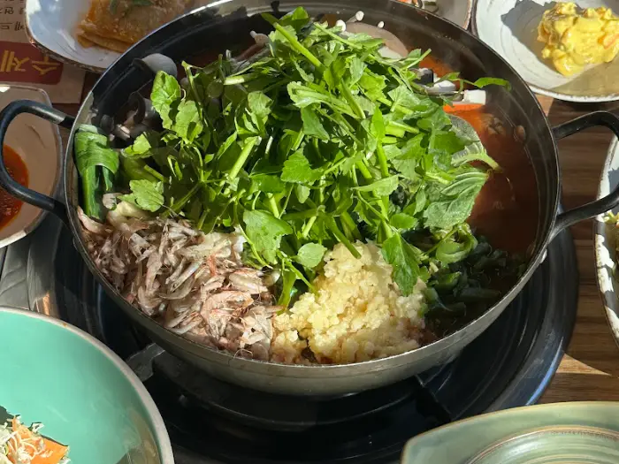 국물이 가득 담긴 매운탕 냄비와 다양한 채소