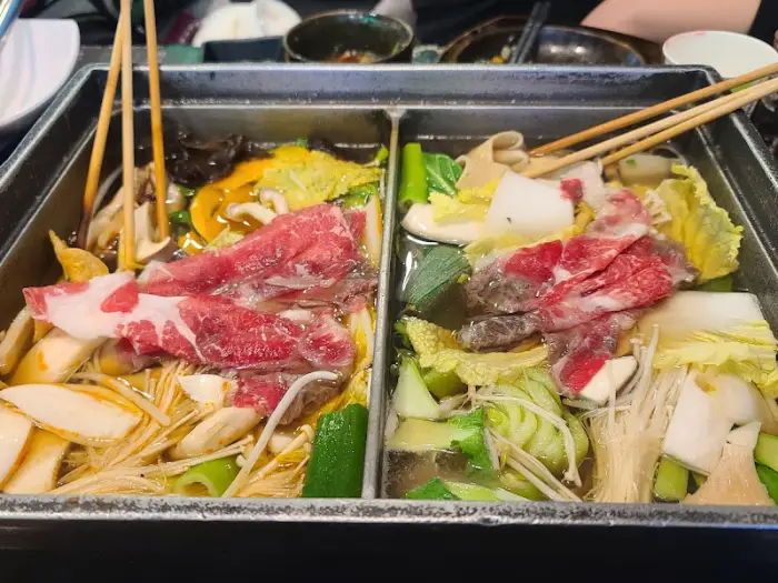 두 칸으로 나뉜 솥에 편백찜과 샤브샤브 재료가 담겨 있는 모습