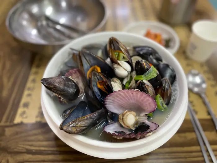 주황색 홍합과 조개, 키조개가 보이는 칼국수 그릇.