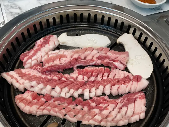 불판 위에 올려진 삼겹살과 버섯. 칼집이 정교하게 나 있다.