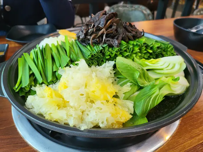 삶기 전의 닭백숙 재료들. 큼직한 닭고기 위에 능이버섯, 각종 채소들이 보기 좋게 쌓여 있다.