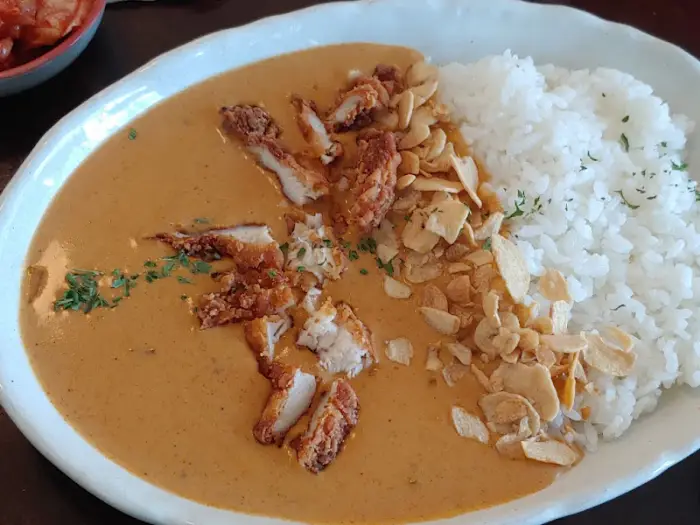 카레라이스 위에 튀긴 치킨 조각과 슬라이스 아몬드가 뿌려진 모습