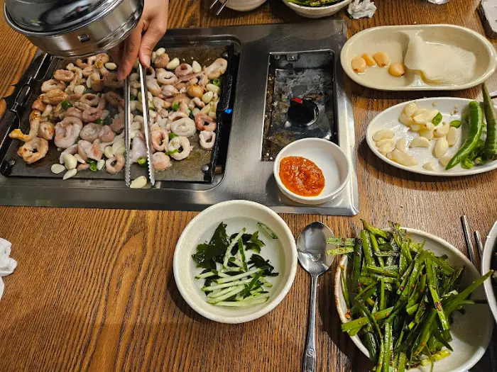 테이블 위에 놓인 다양한 반찬과 볶아지고 있는 곱창