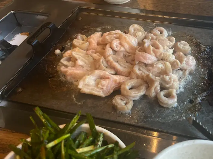 석쇠 위에서 익어가고 있는 곱창과 곁들여지는 부추