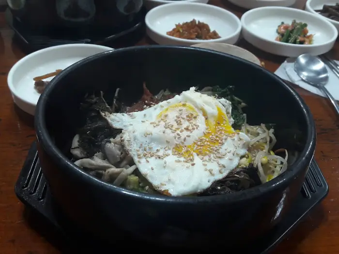 김이 솔솔 나는 비빔밥 한 그릇, 계란 프라이가 얹혀 있습니다.