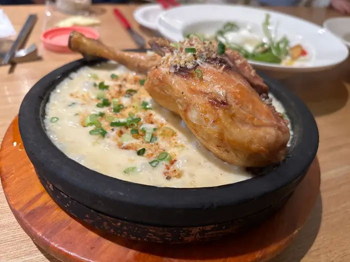 바삭하게 튀겨진 닭다리가 덮인 하얀 크림 리조또.