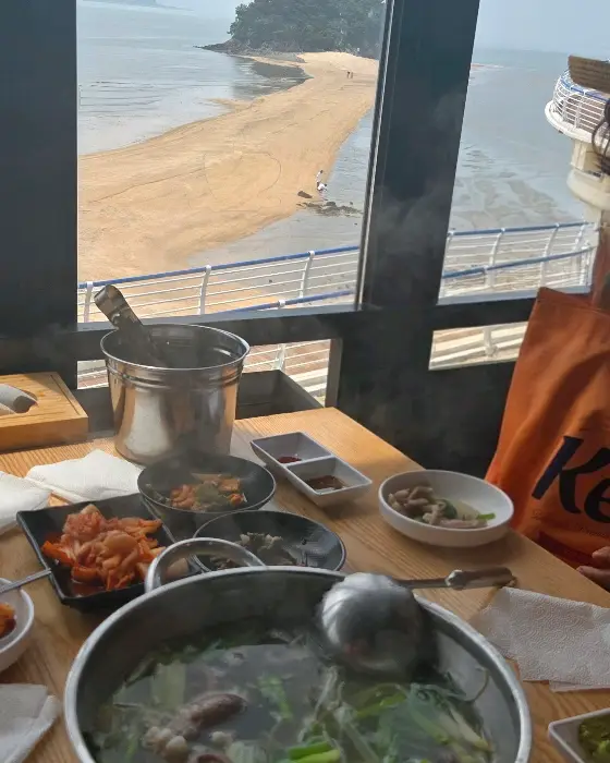 식탁 위에 놓인 음식들과 창밖 바다 풍경