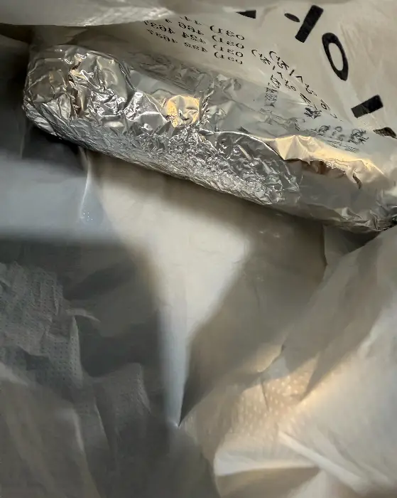 김밥이 비닐봉투에 담겨 있습니다. 봉투에는 글자들이 인쇄되어 있습니다.