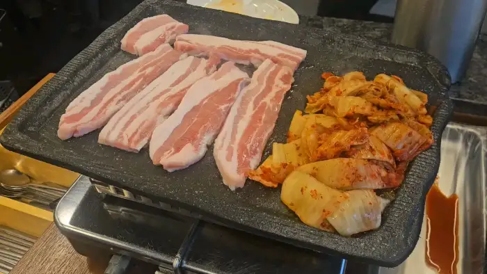 잘 익은 삼겹살 한 점을 쌈에 싸먹는 모습