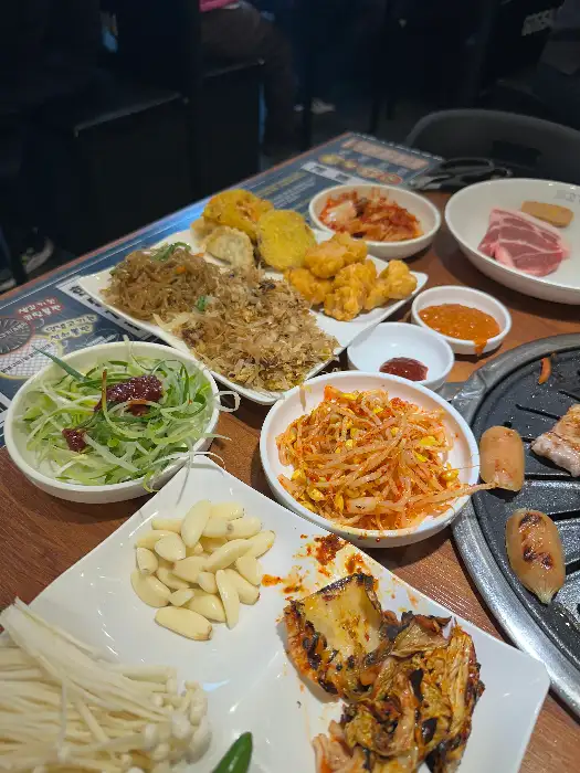 다양한 종류의 곁들임 반찬과 고기가 차려진 식탁