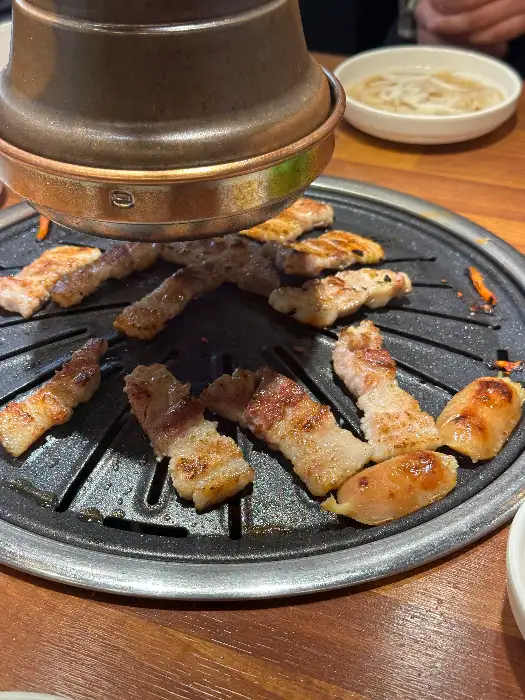 불판 위에서 맛있게 구워지고 있는 삼겹살과 소시지